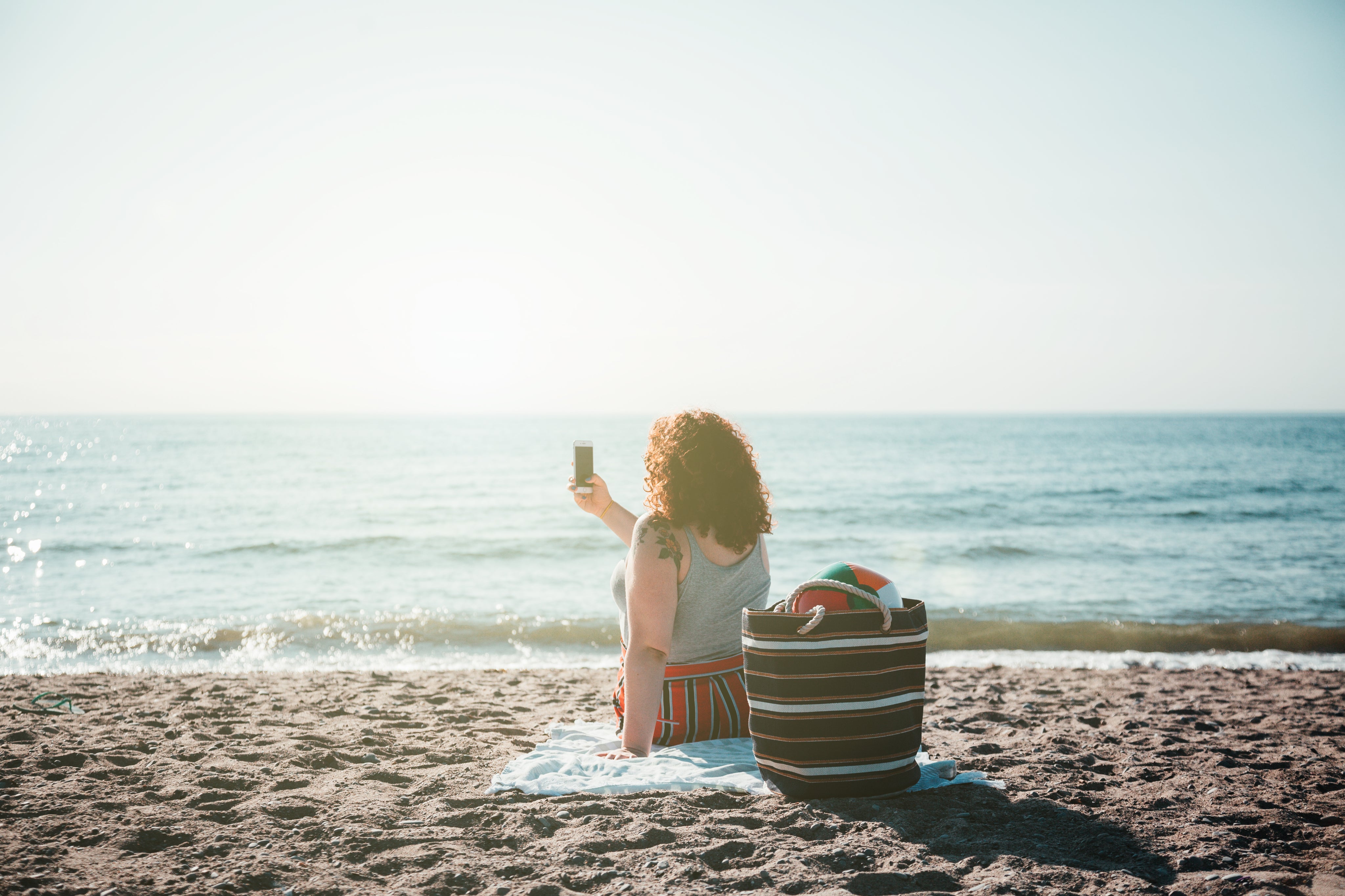 files/young-woman-takes-selfie-while-sitting-on-sunny-beach.jpg